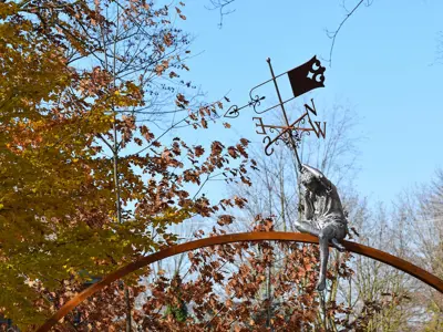 Sculpture of a young boy with a weather vane atop a large arch